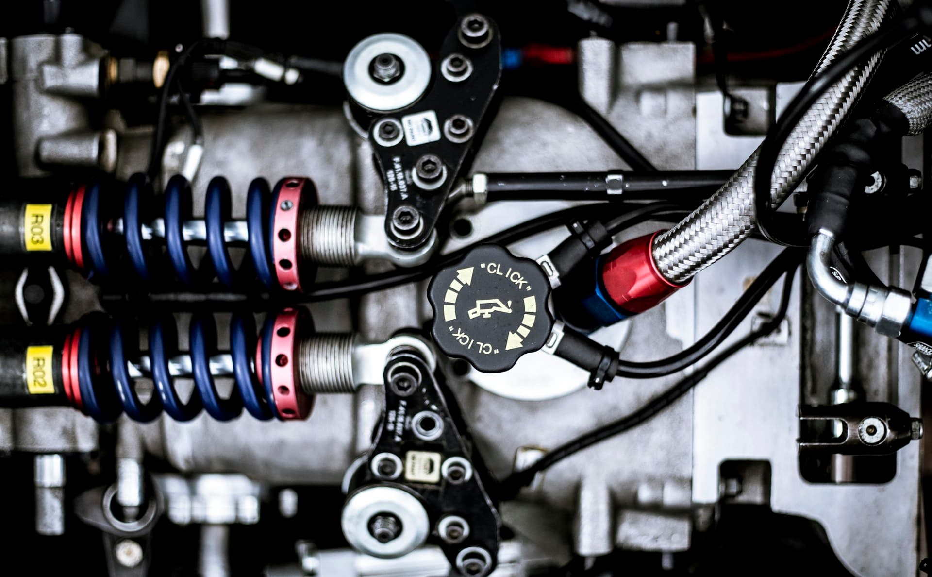 Close-up of a machined mechanical assembly with springs and braided hoses